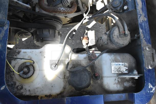 Engine compartment of EZ Go Blue and White 6 Seat Golf Cart, showing components and wear. Label visible. Needs cleaning.