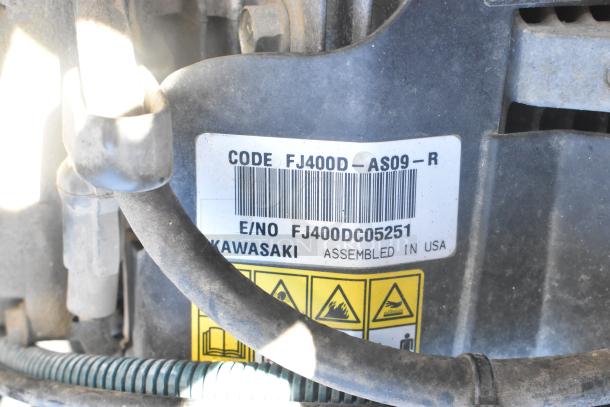 Label on EZ Go golf cart engine showing model code FJ400D-AS09-R, serial number FJ400DC05251, assembled in USA.