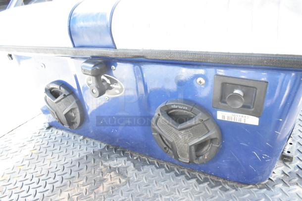 EZ Go blue and white 6-seat golf cart with speaker system, visible speaker, and serial number 3091843 on blue body.