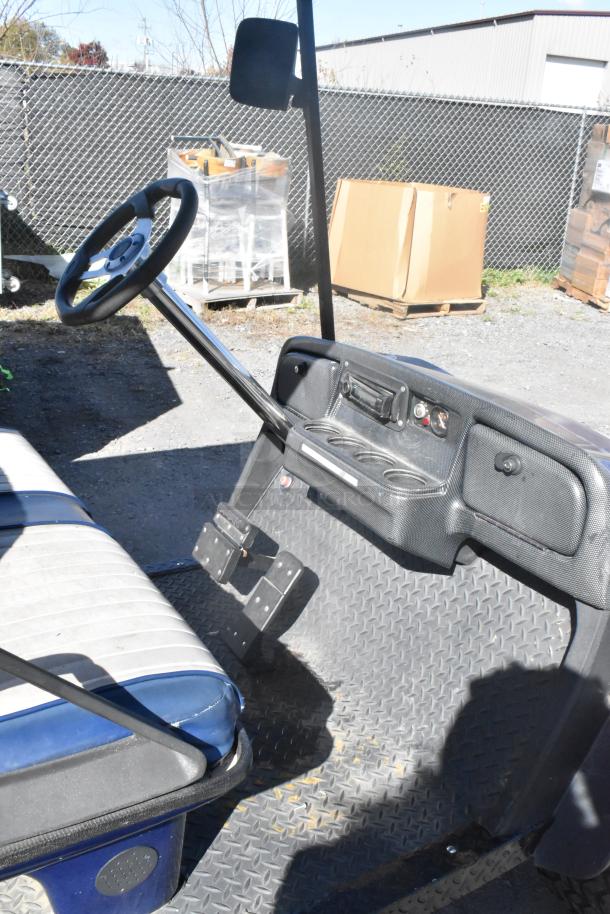 EZ Go blue and white 6-seat golf cart with speaker system, features cup holders and diamond plate floor, in good condition.