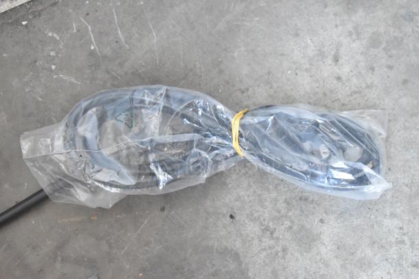 Sealed power cord wrapped in plastic with a rubber band on a concrete surface.