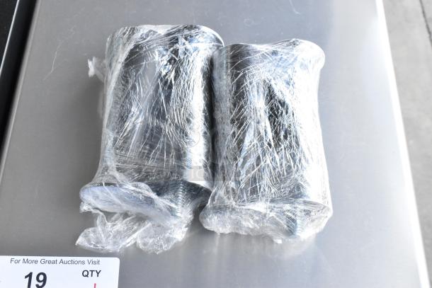 Two metal ice machine components wrapped in plastic, on display for auction. Appears new, part of Scotsman CU0715MA-1A.