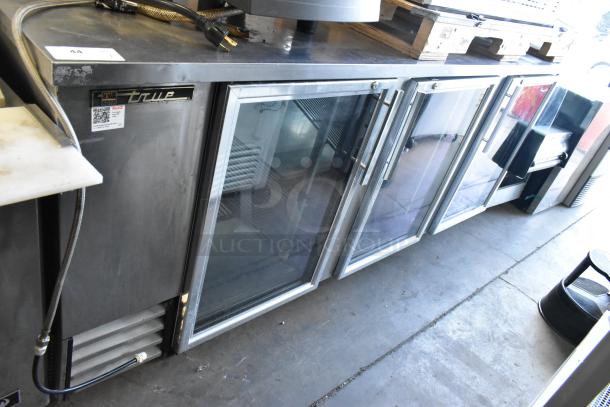 True TBB-4G-S-LD 3-door back bar cooler with glass doors, stainless steel finish, 115 volts, and model label visible.