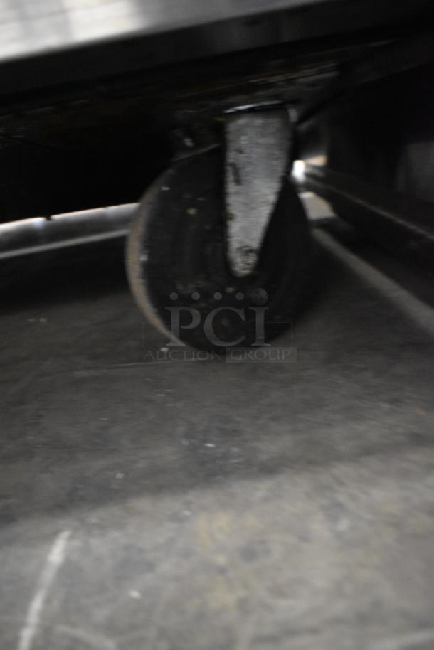 Close-up of a black commercial caster wheel on the True TSSU-72-30MB-ST-HC sandwich salad prep table.