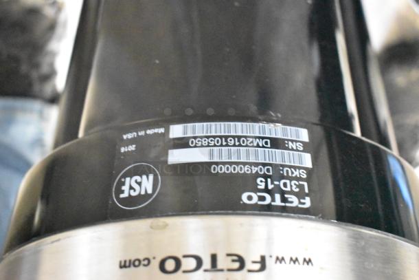 Fetco Luxus L3D-15 stainless steel beverage holder with drip tray; SKUs and serial numbers visible. Made in USA.