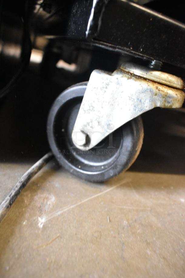 True T-72F commercial freezer caster wheel detail on concrete, showcasing mobility. Item includes poly-coated racks.