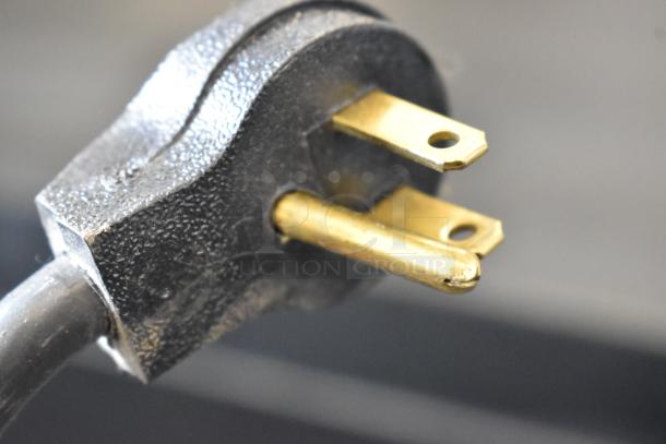 Close-up of a black and gold electrical plug for the Imbera VRD41 commercial cooler, showing a three-prong design.