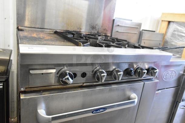 Cookrite stainless steel commercial gas range with 4 burners, flat top griddle, oven, over shelf, and back splash on casters.