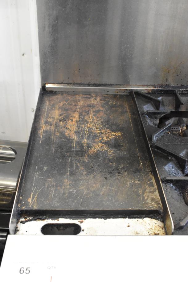 Cookrite stainless steel 4-burner gas range with flat top griddle. Features over shelf, oven, and backsplash, on casters. Used condition.