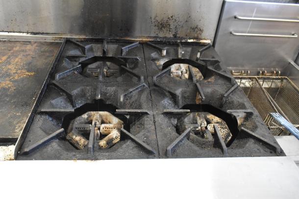 Cookrite stainless steel 4-burner gas range with flat top griddle, oven, over-shelf, and backsplash on commercial casters.