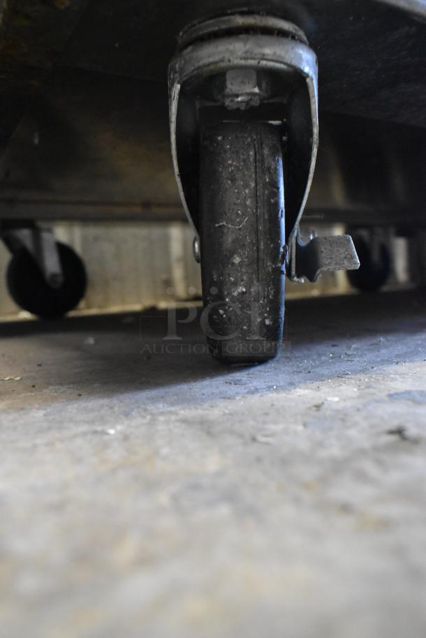 Close-up of a commercial caster wheel on a Cookrite Stainless Steel 4 Burner Range. Sturdy design with locking mechanism.
