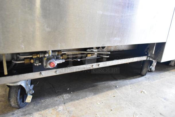 Cookrite stainless steel commercial range, gas-powered, 4 burners, flat top griddle, oven, over shelf, back splash, on casters.