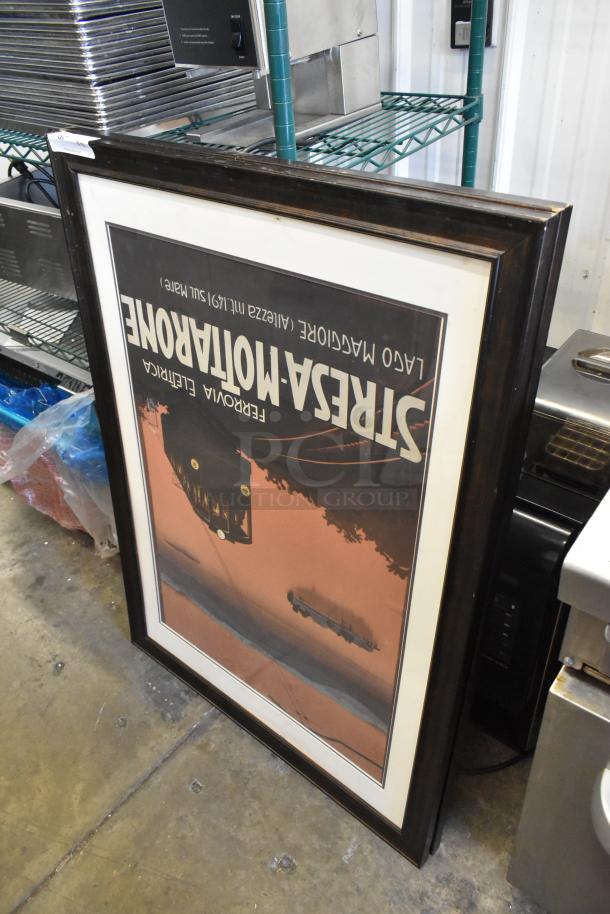 Framed vintage travel poster with dark wood frame, featuring scenic artwork. Appears in good condition.