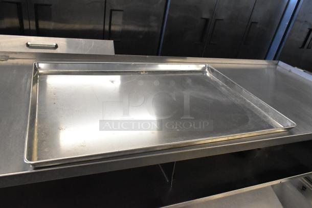 Full-size metal baking pan, slightly used, on a stainless steel surface. Auction includes 24 pans.