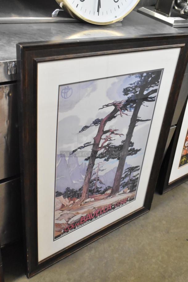 Framed artwork featuring a landscape of trees and mountains, labeled "Col de Bavella Corse," with a large wall clock above.