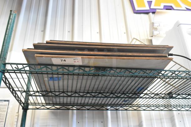 Five framed pictures stacked on a metal shelf, labeled "74 QTY x5." 