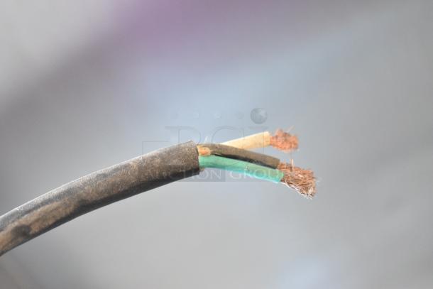 Frayed electric cord with exposed copper wires in a commercial setting. Safety hazard, requires repair.