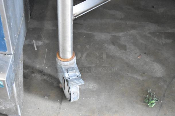 Bakers Pride CBBQ30S stainless steel charbroiler on commercial casters, shows wear. Propane gas powered with cover.