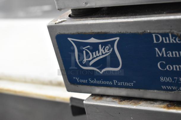 Duke stainless steel convection oven with view-through doors, metal racks, and thermostatic controls, logo and contact info visible.