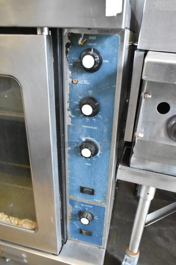 Duke stainless steel commercial convection oven with view-through doors, thermostatic controls, and metal racks. Signs of wear visible.