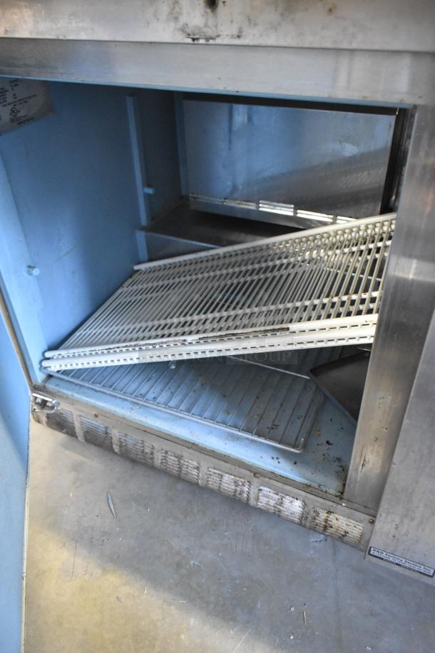 Delfield 4460N-24M stainless steel prep table, interior view, showing racks and shelving. 115 volts, 1 phase. Used condition.