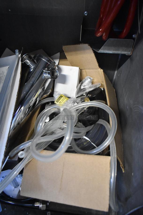 Box with components for Perlick DDS36 beer dispenser, including tubing and chrome parts. Some items wrapped in plastic.