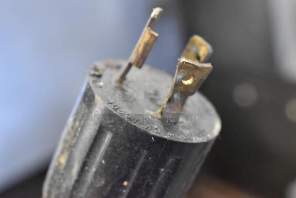 A close-up of a plug part, slightly corroded, with visible prongs and imprinted markings.