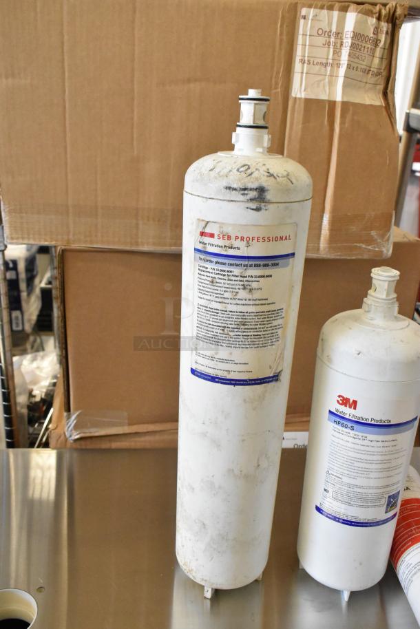 Six various water filter cartridges, including SEB Professional and 3M models, in used condition with labels visible.