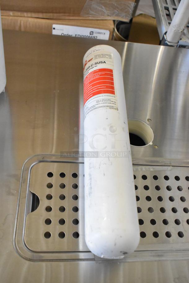 Six water filter cartridges on a metal surface, labeled for sediment filtration, slightly used condition.