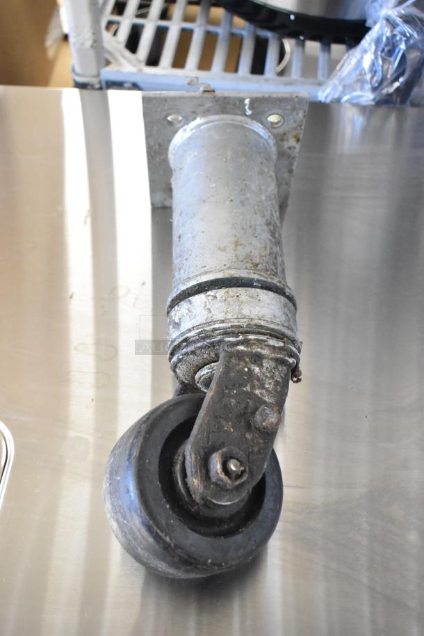 Lot of 4 commercial casters, metal and rubber, used condition, showing wear and rust, suitable for heavy-duty equipment.