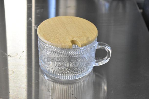Brand new glass mug with wooden lid, decorative pattern, clear handle, perfect condition. Part of a lot of 4.