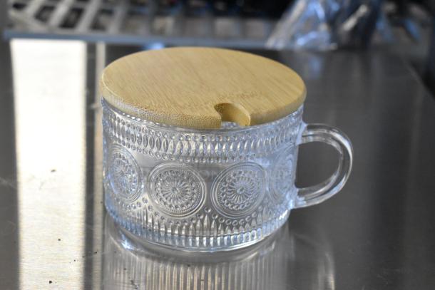 Brand new glass mug with textured design and wooden lid. Item part of a lot of four.
