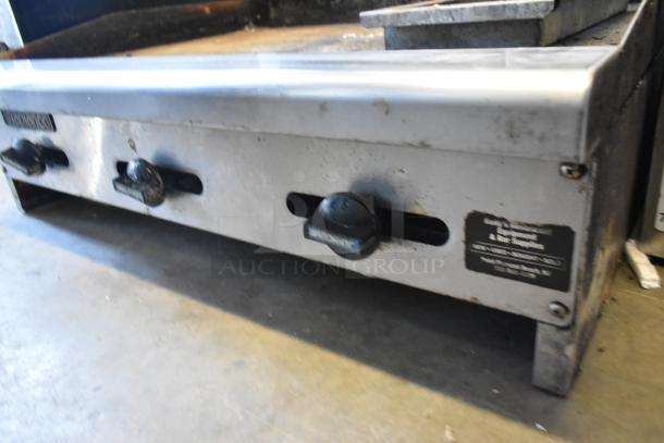 Radiance stainless steel commercial natural gas flat top griddle, with front control knobs, visibly used condition.