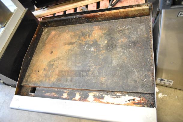 Radiance stainless steel flat top griddle, commercial, natural gas powered, showing signs of heavy use on cooking surface.