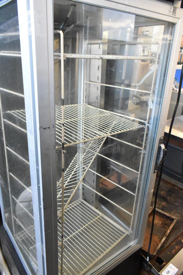 Metal commercial heated holding cabinet with racks, unable to open door, needs new handle, visible wear, glass panels.