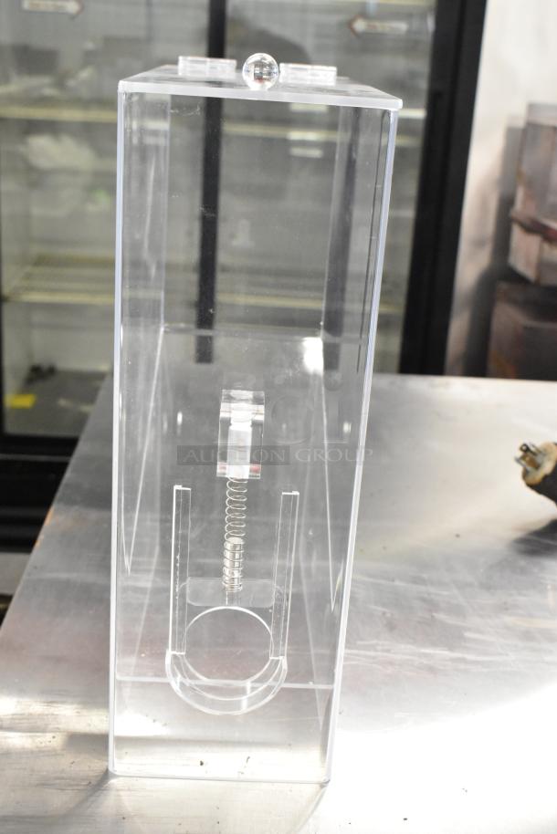Clear poly dry ingredient dispenser, brand new with minor scratches, featuring a spring mechanism and lid. Ideal for various uses.