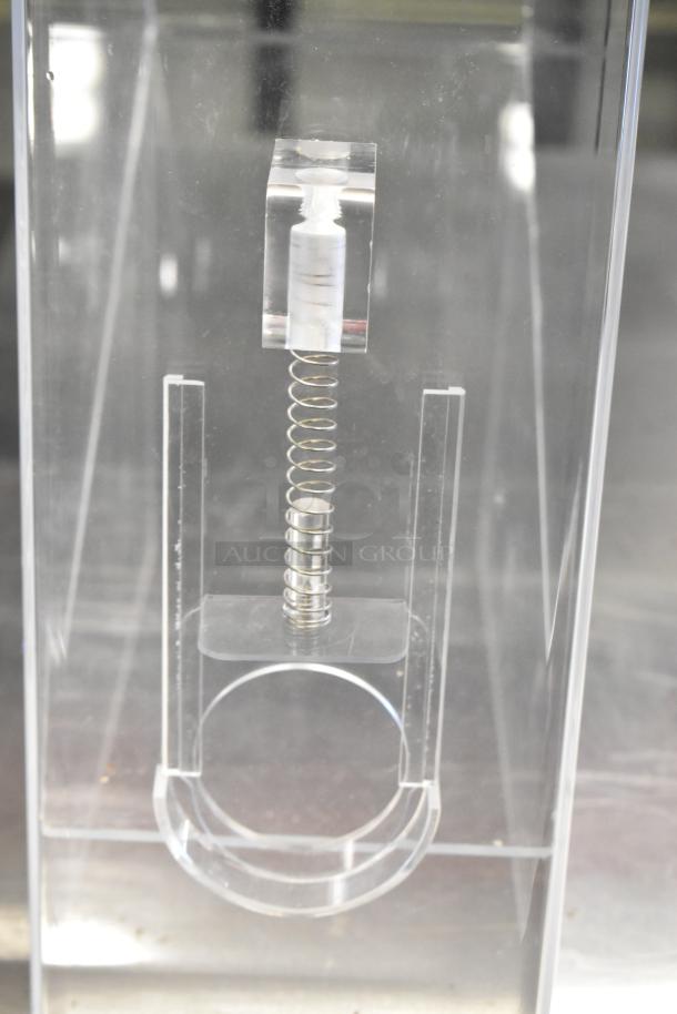 Clear poly dry ingredient dispenser with spring mechanism, brand new, part of a set including a countertop cup and lid organizer.