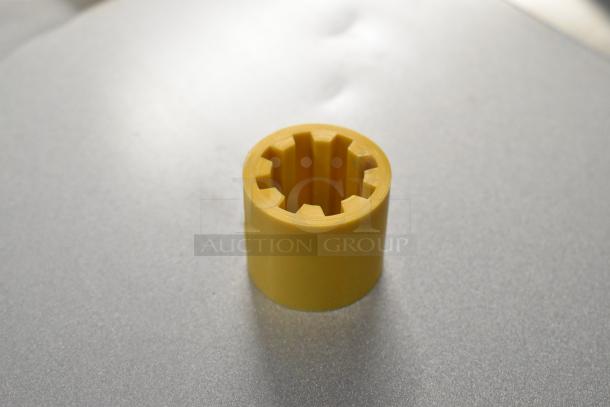 Yellow rubber coupling center, Lincoln part HP369664, new condition, gear-like interior design.