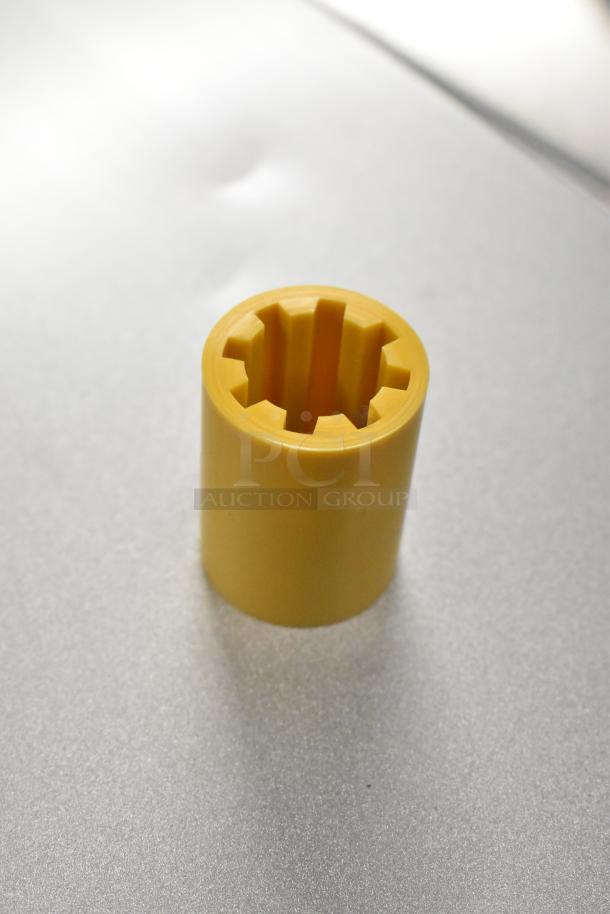 Yellow rubber coupling center, Lincoln HP369664, new, cylindrical with internal grooves, on gray surface.