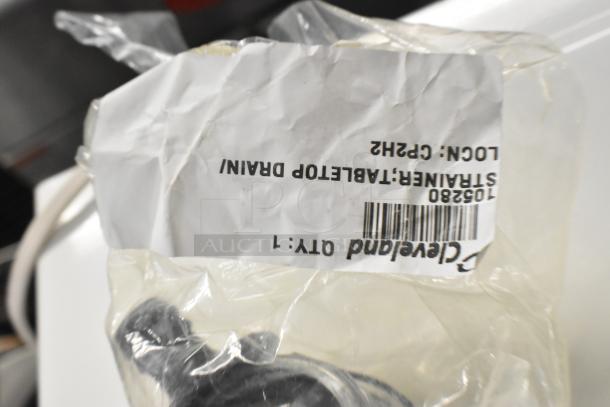 Plastic-wrapped Cleveland 06230 Fitting, labeled "Strainer: Tablet Drain" and "Qty: 1". Appears new, for auctions.