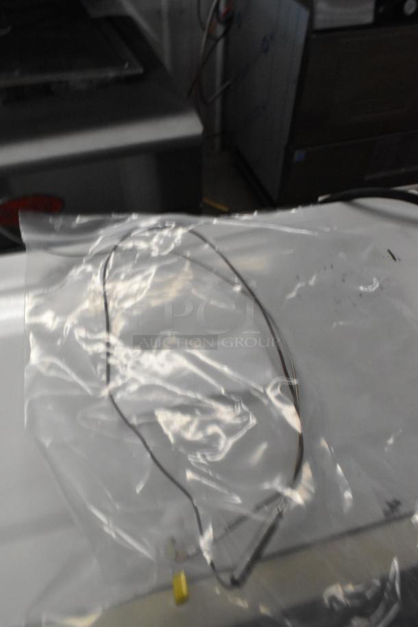 Clear bag containing a new thermocouple, part of an auction lot including diverse cooking equipment parts.