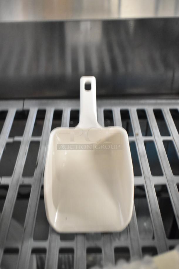 White poly scooper with handle, brand new, slight scratches visible. Auction includes seven assorted scratch and dent items.