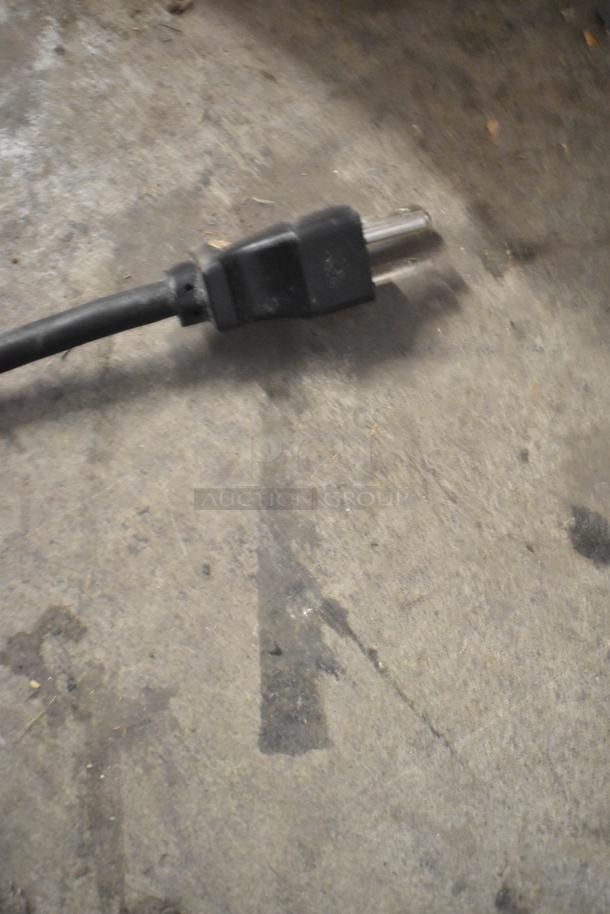 A power plug for the Bunn VP17-2 coffee machine shown on a concrete surface.