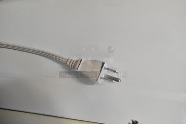 Close-up of a three-prong power plug on a white cord.