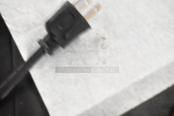 Blurry image of a black electrical plug on a white surface, details unclear.