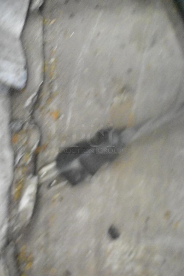 Blurry image of an electrical plug on a surface, indistinct and difficult to discern details or context.