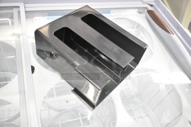 Black metal organizer with two slots, minor scratches visible, resting on a reflective surface.