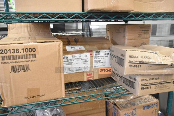 Boxes of new "scratch and dent" items on metal shelving. Includes Rubbermaid Auto Foam Refill and Health Gards Waxed Paper Liners.