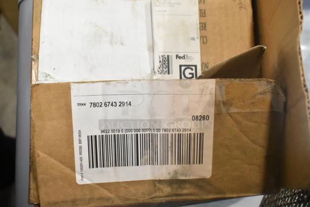 Cardboard boxes with shipping labels and barcodes, part of a larger auction lot including a metal fry basket and skimmer.