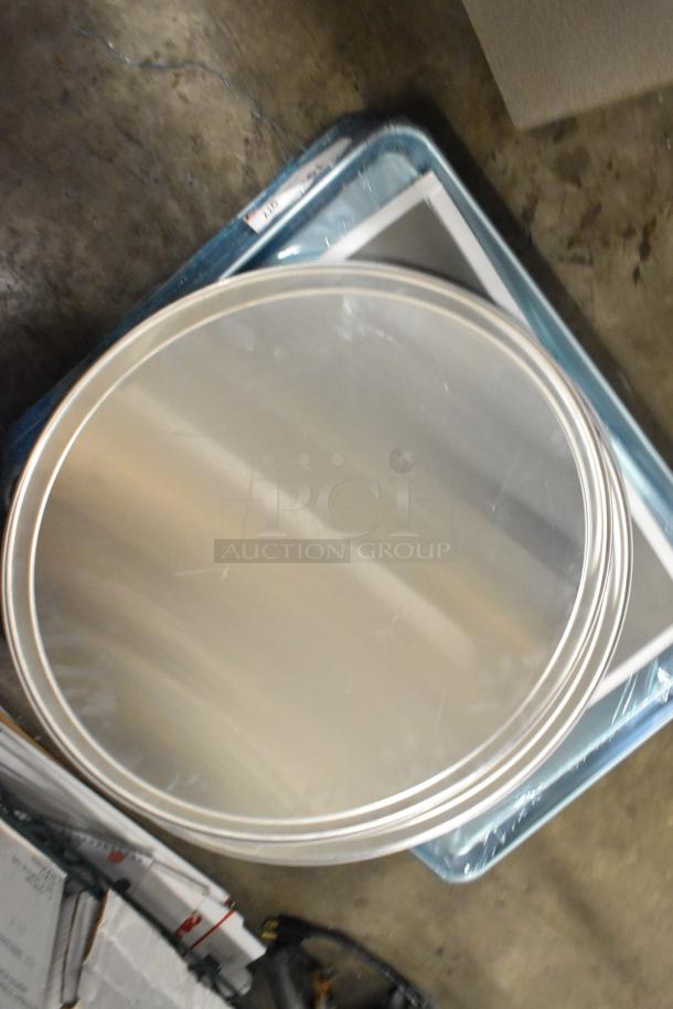 27 new scratch and dent items, including steam table pans, loaf pans, pizza pans, and sheet pans, stacked.